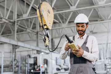 An Indian worker in a special uniform and helmet controls the lift manually.