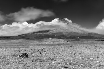 The Cotopaxi volcano, fields and meadows, rocks and moving straw, all part of a wonderful scene at the Cotopaxi National Park, Ecuador. Black and White photography. ND filters used for movement.