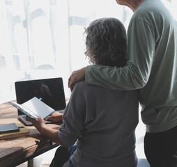 Embraced mature couple surfing the Internet on laptop at home