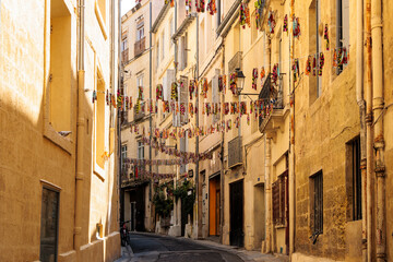 A narrow alley decorated with colorful flags in the downtown of the French city of Montpellier in...