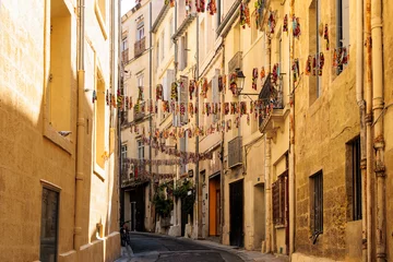 Papier Peint photo autocollant Ruelle étroite A narrow alley decorated with colorful flags in the downtown of the French city of Montpellier in France