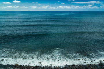 Beautiful seascape with small waves breaking on a pebble beach in the north of Gran Canaria. Atlantic Ocean.