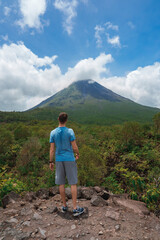 Rear view of male traveler admiring the Arenal volcano and idyllic landscape of Costa Rica mountain © Aerial Film Studio