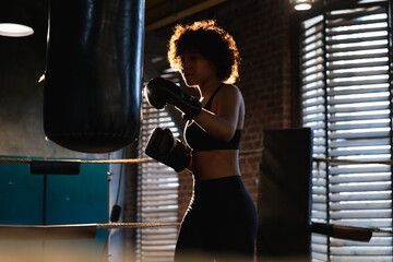 Women self defense girl power. African american woman fighter training punches on boxing ring. Healthy strong girl punching boxing bag. Training day in boxing gym. Strength fit body workout training