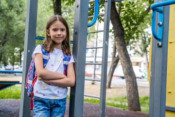 Portrait of beautiful school girl with backpack staying on playground