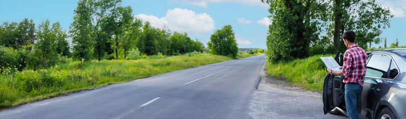 A man on the road is looking at a map. Selective focus.