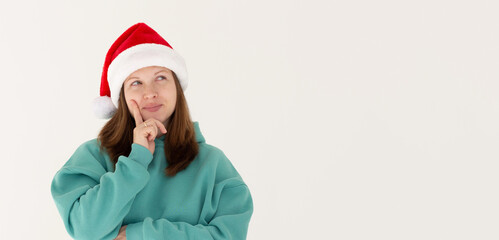 Photo of funny pretty pregnant lady celebrate winter holidays dreamy look empty space think family party hand on chin x-mas concept wear santa cap isolated white color background