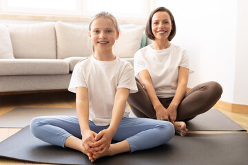Positive millennial caucasian woman in sportswear and teenage daughter practice yoga, training