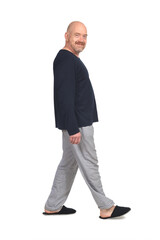 Fototapeta premium side view of a man in pajamas walking and looking at camera on white background