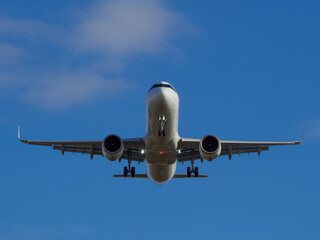 Naklejka premium White passenger airplane flying in the sky clouds in the background -