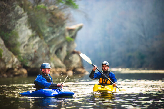 A father and son paddle kayaks alongside bluffs lining the Chattahoochee River near Powers Island, Atlanta, Georgia