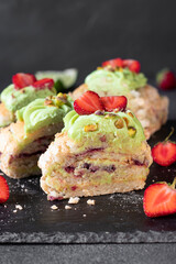 Meringue roll with strawberries and pistachios on dark gray background