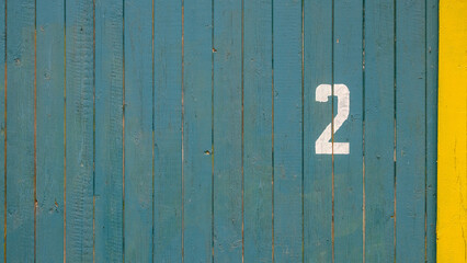 The number two is written in white paint on the green wall of the house of daughters, 2