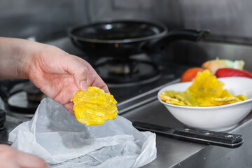 close-up of a woman's hand stepping on fried plantains to make patacones