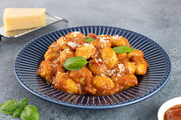 Italian traditional gnocchi with tomato sauce, parmesan cheese and fresh basil on a blue background. Italian food. 