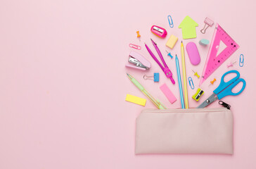 Pink pencil case with school stationery on color backgroung, top view