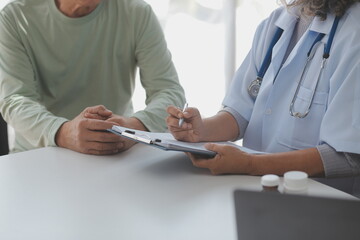 Mature Asian male doctor talking with his patient, explaining the procedure to old lady.