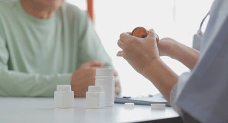Mature Asian male doctor talking with his patient, explaining the procedure to old lady.