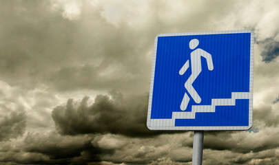 Sign pointer to the underpass against the background of a gloomy cloudy sky