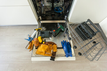 repair of a modern dishwasher with screwdrivers in the kitchen