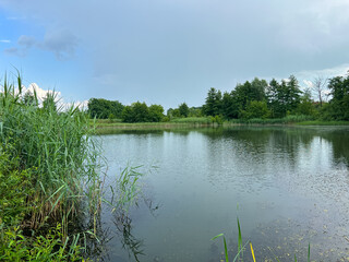 A beautiful small lake in the countryside. Sunny day with clouds in the sky. Perfect place for relaxing