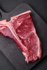 Raw juicy beef t-bone steak with salt, spices and herbs