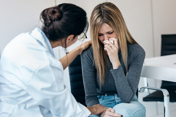 Fototapeta premium Beautiful worried woman crying while doing therapy with her female psychologist at the medical consultation
