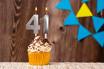 burning candle - birthday number 41 on wooden background with pennants