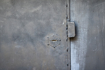 Fragment of a black rough iron door. There is a keyhole and a simple metal handle. Background. Texture.