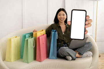 Positive young chinese woman showing shopping mobile app