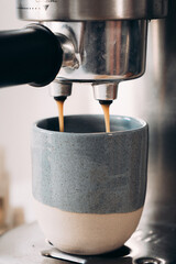 Machine à café expresso en action dans une tasse en céramique - obrazy, fototapety, plakaty