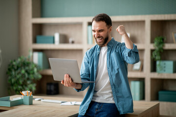 Business Success. Young Happy Businessman Celebrating Success With Laptop In Office