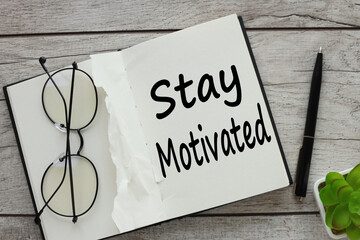 Stay motivated! notepad with text. glasses on a notebook page.