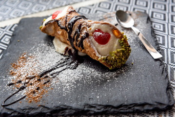 Italian Sicilian cannolo pastry dessert closeup on black stone plate macro with texture of yellow...