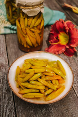 pickled daylily flowers in glass jars on a wooden surface in the garden on a summer day