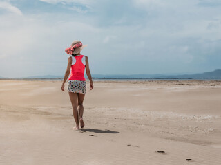 a woman walks on the sand of the beach in a relaxed way. concept of vacation and tranquility. mental health and balance.