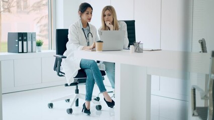 Video of  two beautiful female doctors working with her laptop while talking in the medical consultation
