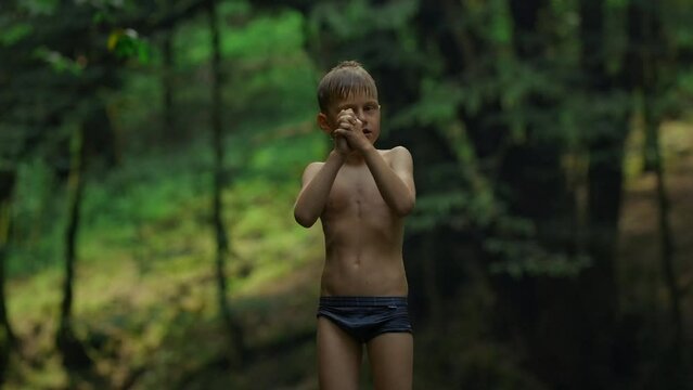 Caucasian boy Mowgli enjoys nature, wet after swimming. Creative. Boy child in swimwear with green jungles on the background.