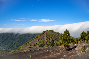 Clouds move over the mountain slope of Cumbre Nueva and flow into the valley like a waterfall, La Palma, Canary, Spain, Europe