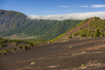 Clouds move over the mountain slope of Cumbre Nueva and flow into the valley like a waterfall, La Palma, Canary, Spain, Europe