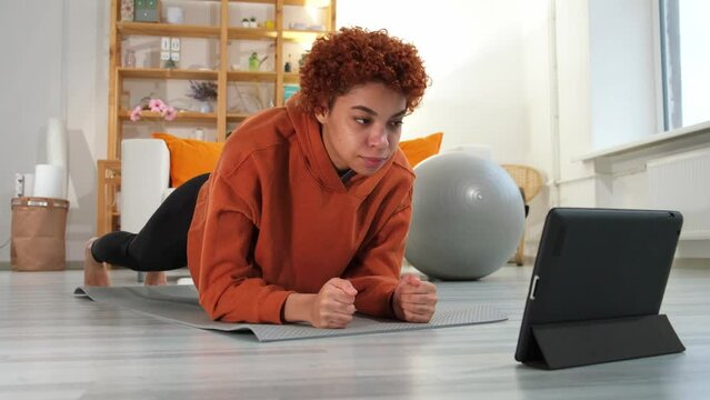 Fitness Workout training. Young healthy fit african girl doing plank exercise on yoga mat on floor at home. Athletic woman in sportswear training pilates. Sport and fitness