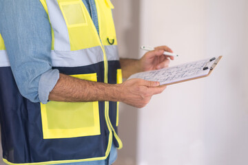 Experienced worker checking and correcting construction documents holding clipboard and pen in...
