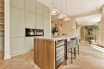 a modern kitchen with wood flooring and light green cabinetry in the center of the room is an island