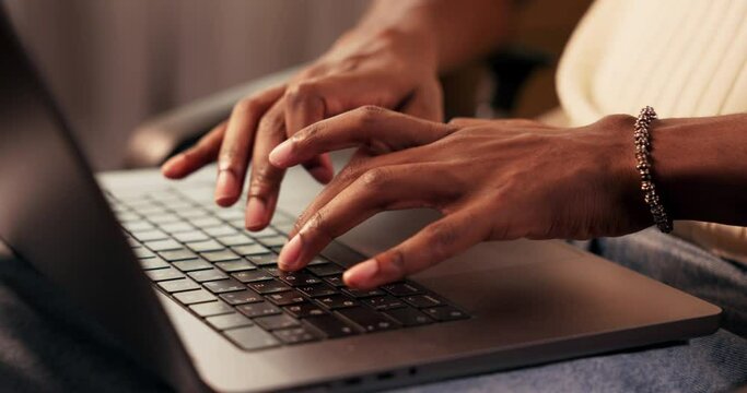Close-up of hands of African American man tapping fingers on keyboard on laptop while working.