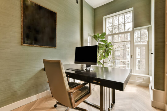 a home office with a desk and chair in front of a large painting on the wall behind it is a window