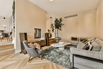 a living room with wood flooring and beige wallpapers on the walls there is a couch, coffee table, two chairs