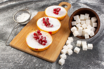front close view delicious cranberry cakes with red cranberries on top sugar pieces and sugar powder grey desk cake biscuit sweet bake