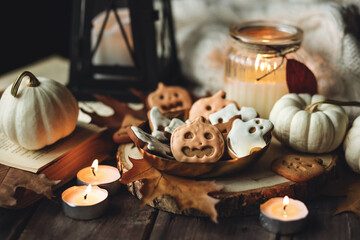 Autumn home composition with aromatic candle, pumpkin, wool sweater, halloween homemade cookies. Aromatherapy on a grey fall morning, atmosphere of cosiness and relax. Holiday handmade decor
