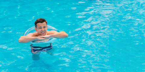 Portrait of a cheerful middle-aged man in the pool with inflatable lifebuoy.