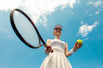 girl tennis player in white uniform holds racket and ball on the tennis court, woman athlete plays tennis